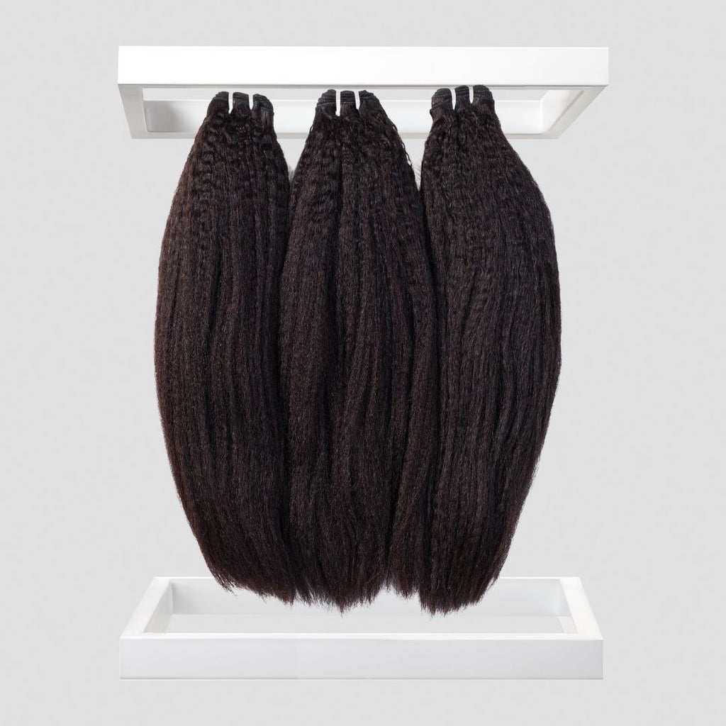 Three bundles of black hair extensions on a white background