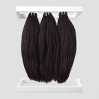 Three bundles of black hair extensions on a white background