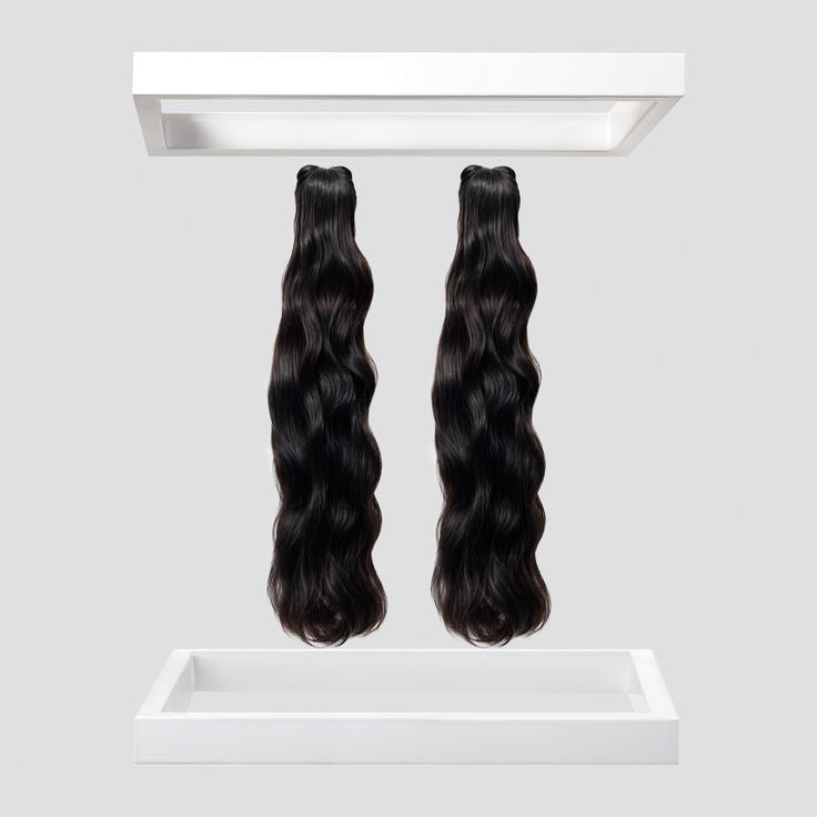 Two bundles of wavy black hair extensions on a white background