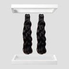 Two bundles of wavy black hair extensions on a white background
