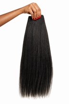 Black hair extensions held by a hand on a white background